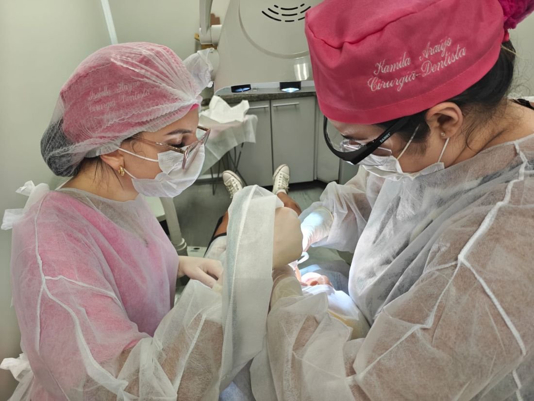 Dra. Kamila e uma colega cirurgiã-dentista realizando um procedimento a quatro mãos.